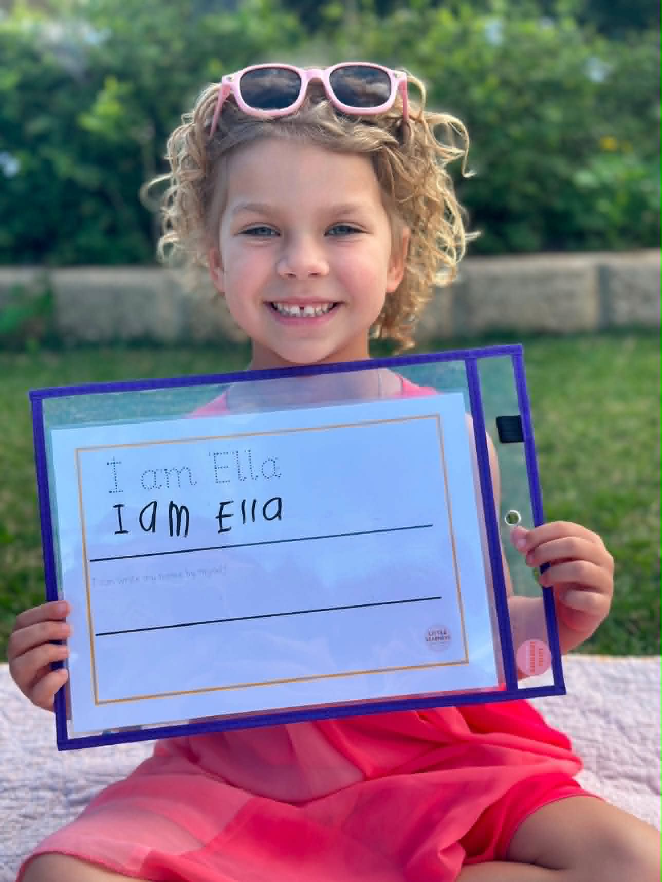 Child holding personalised 'I am Ella' name tracing card