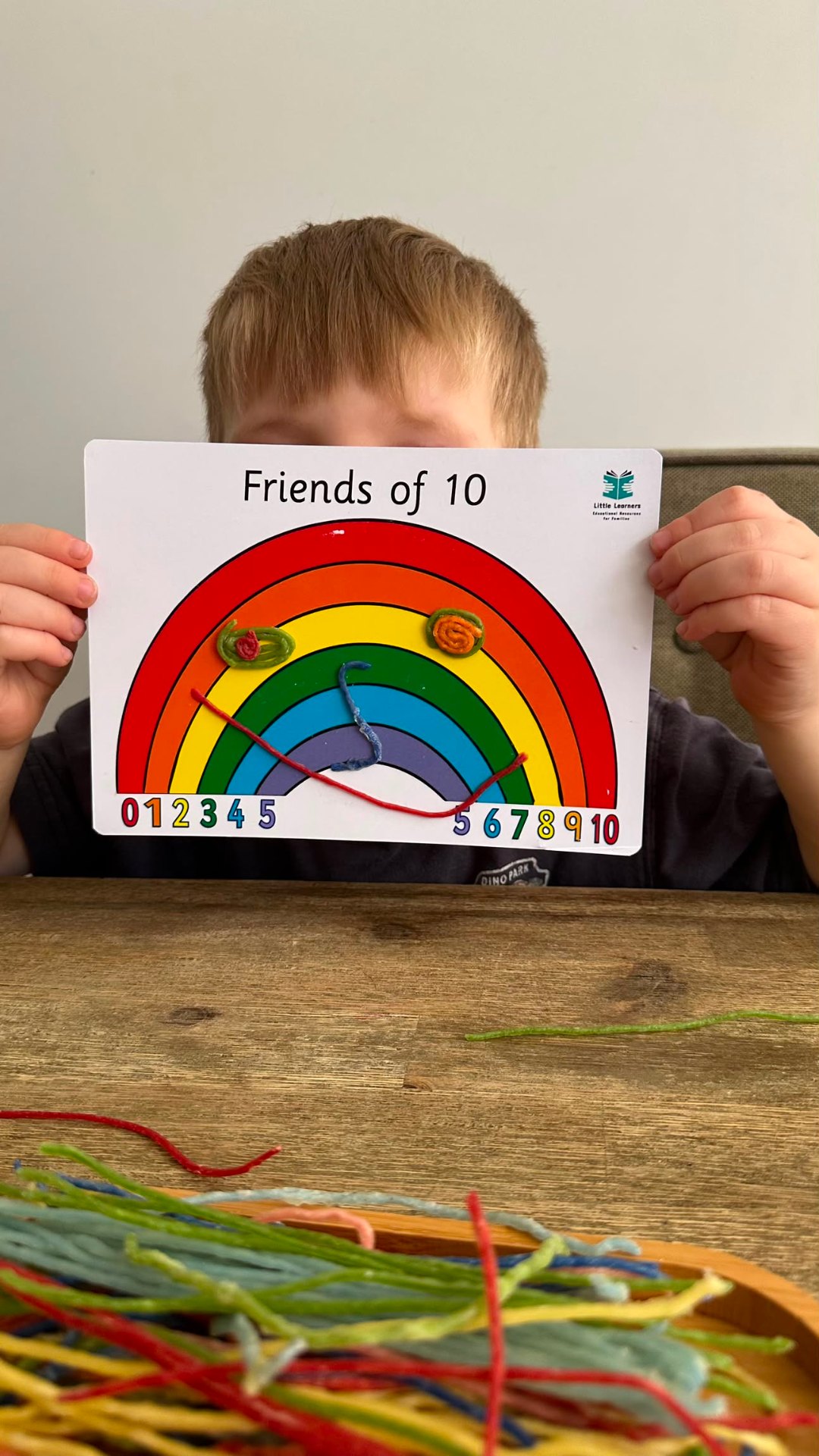 Child holding Friends of 10 rainbow number board